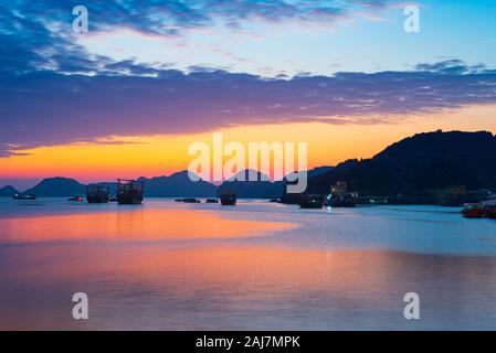 Ciel coucher de soleil uniques au Vietnam avec la baie de Cat Ba village de pêcheurs flottant sur la mer, bateau cloudscape climat tropical, d'une exposition longue, blurred motion. Banque D'Images