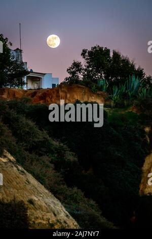 La pleine lune au-dessus de la falaise sur la plage à Albufeira au Portugal. Photo : Tony Taylor Banque D'Images