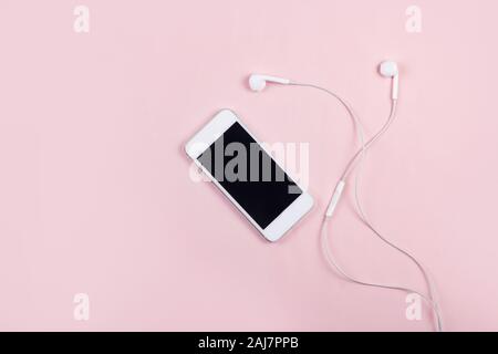 Téléphone mobile avec écouteurs sur fond rose Vue de dessus Banque D'Images
