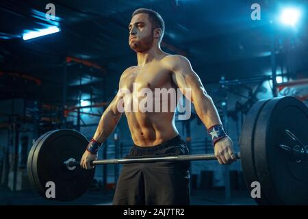 Caucasian man pratiquer en haltérophilie dans la salle de sport. Homme de race blanche modèle sportif de formation, semble confiant et fort. Musculation, bonne hygiène de vie, de mouvement, d'activité, concept d'action. Banque D'Images