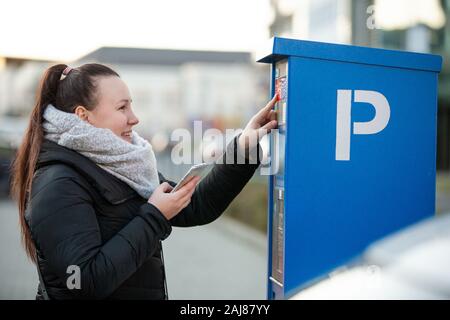 Femme l'achat d'un parking pour sa voiture par le smartphone, mobile Banque D'Images