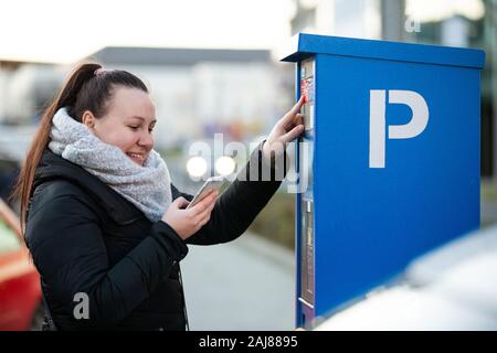 Femme l'achat d'un parking pour sa voiture par le smartphone, mobile Banque D'Images