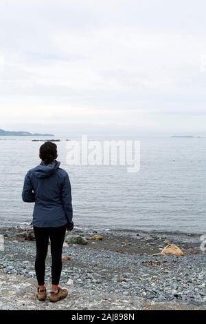 Femme regardant la mer à Witless Bay à Terre-Neuve et Labrador, Canada. La journée est couvert. Banque D'Images