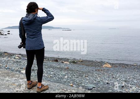 Femme regardant la mer à Witless Bay à Terre-Neuve et Labrador, Canada. La journée est couvert. Banque D'Images