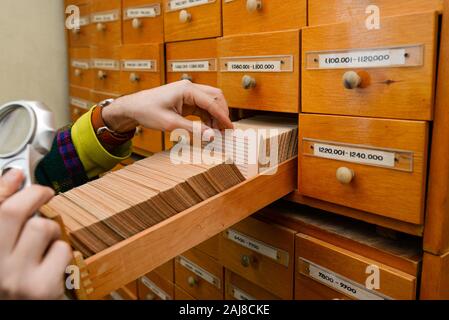 Un homme est à la recherche d'information dans une boîte avec des cartes en papier. Recherche de données et d'informations. Le stockage des données dans la bibliothèque ou dans le bureau. Base de données. Banque D'Images