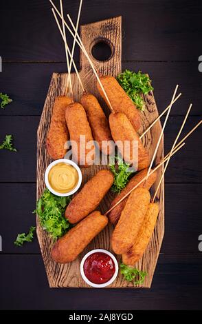 Le maïs traditionnel américain les chiens avec de la moutarde et du ketchup sur planche de bois. L'alimentation de rue. Vue de dessus, copy space Banque D'Images