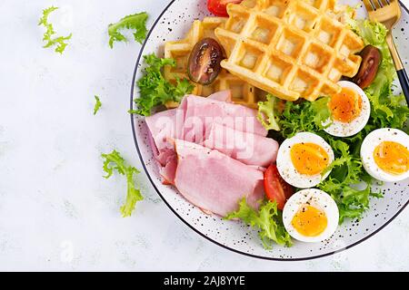 Petit déjeuner avec des gaufres de semoule, oeuf dur, jambon et tomate sur fond blanc. Apéritifs, brunch, en-cas. Alimentation saine. Vue de dessus, les frais généraux, spa copie Banque D'Images