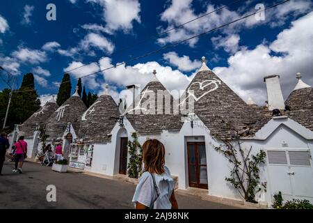 ALBEROBELLO, ITALIE - 28 août 2018 - Belle vieille ville d'Alberobello avec de superbes carreaux de pierre blanchis à cône Trulli dans les Pouilles maisons de toit est visité chaque année par des millions de touristes. Des signes. Banque D'Images