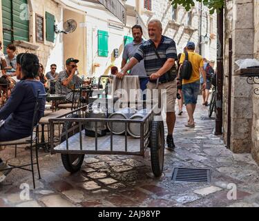 Le Monténégro, Sep 21, 2019 : scène de rue avec un homme la prestation de fûts de bière via panier de roue dans la vieille ville de Kotor Banque D'Images