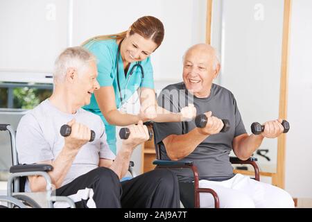 Deux personnes âgées en fauteuil roulant lors de la formation de forme physique avec haltères en la maison de soins infirmiers Banque D'Images