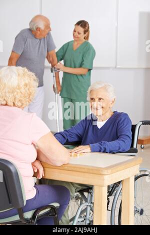 Les personnes âgées sont deux vieux jouent au bingo à la table dans la maison de soins infirmiers Banque D'Images