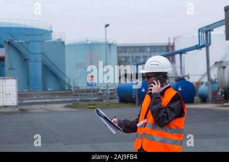 travailleur avec un casque près des réservoirs Banque D'Images