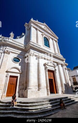 Bari, Italie - 28 août 2018 - Locorotondo dans les Pouilles, région des Pouilles, Italie du Sud est une petite ville à l'architecture étonnante, des rues étroites et atmosphère chaude. Avant de l'église, les gens assis Banque D'Images