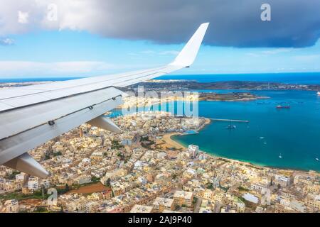 Vue depuis le hublot d'un avion de passagers sur la côte de Malte avec des maisons typiques Banque D'Images