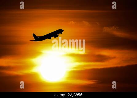 Un avion décolle alors que le soleil se couche sur l'aéroport d'Heathrow à l'ouest de Londres. Banque D'Images