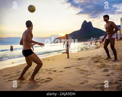 Les gens jouent au football match au coucher du soleil à la plage d'Ipanema à Rio de Janeiro, Brésil. Banque D'Images