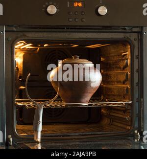 Une argile, un récipient rond, vieux pour la cuisson, écrire dans un four à bois. A proximité se trouve un accessoire, sortez-le du four. Banque D'Images