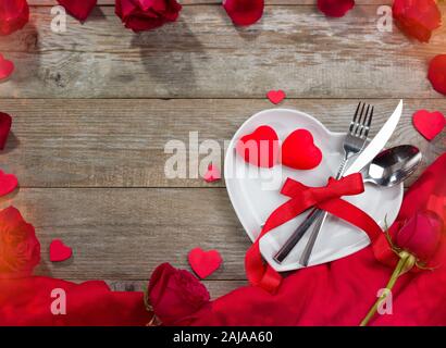 Valentines Day dîner concept. Plaque en forme de coeur, rouge cirée et les roses sur la table Banque D'Images