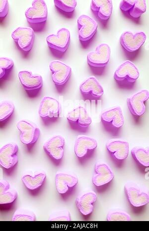 Vertical Image de guimauve en forme de coeur rose violet bonbons éparpillés sur fond blanc Banque D'Images