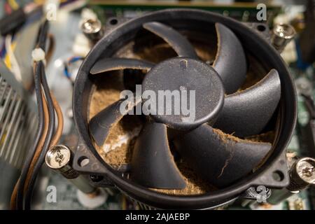 Un ventilateur d'ordinateur très sale à l'intérieur d'un ordinateur est nettoyé par un aspirateur Banque D'Images