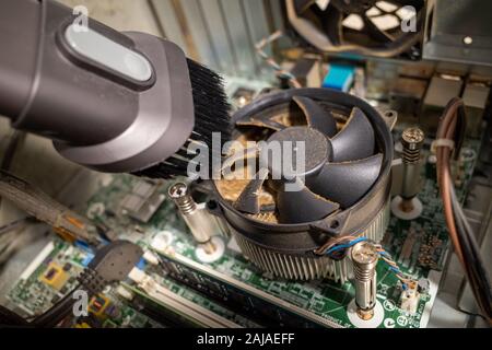 Un ventilateur d'ordinateur très sale à l'intérieur d'un ordinateur est nettoyé par un aspirateur Banque D'Images