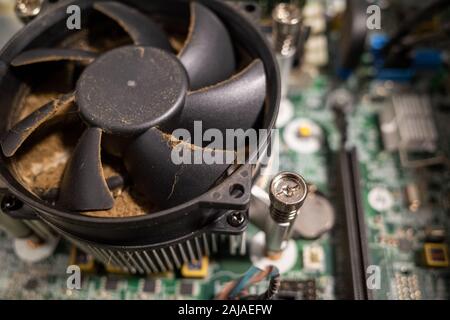 Un ventilateur d'ordinateur très sale à l'intérieur d'un ordinateur est nettoyé par un aspirateur Banque D'Images