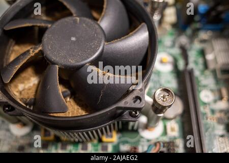 Un ventilateur d'ordinateur très sale à l'intérieur d'un ordinateur est nettoyé par un aspirateur Banque D'Images