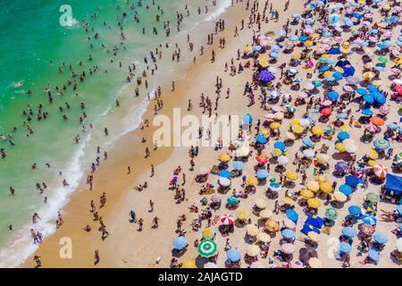 Rio de Janeiro, Brésil, vue aérienne de la plage de Copacabana montrant parasols colorés et les gens se baigner dans l'océan un jour d'été. Banque D'Images