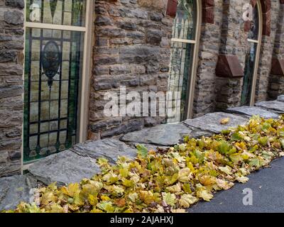 Une ligne de feuilles mortes Allée Pierre le long d'un mur de l'Église Banque D'Images