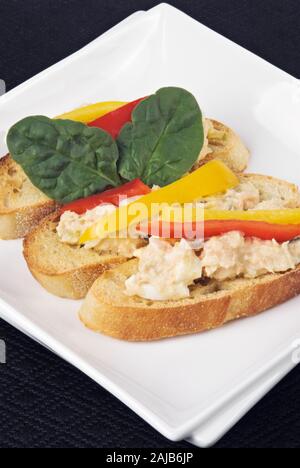 Face ouverte baguette grillées avec des sandwiches thon germon et de saumon rose sauvage. Les poivrons et les feuilles d'épinards sont saisies. Banque D'Images