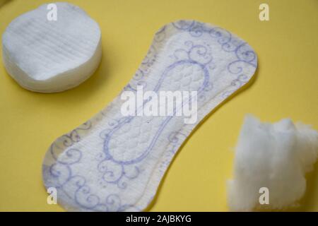 Tampon sanitaire propre floral sur fond jaune, coton-tiges et les pads pour le maquillage, d'hygiène, produits, concept femmes isolées Banque D'Images