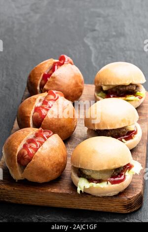 Ensemble de trois mini-hamburgers et hot-dogs servis sur planche de bois Banque D'Images