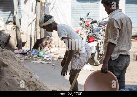 Udaipur, Inde - 05 mars 2017 : Deux jeunes hommes recueillir du sable et de l'exécuter pour fabriquer du béton. Le gars l'air fatigué. Banque D'Images