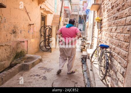 Jodhpur, Inde - le 07 mars 2017 : Un homme qui marche le long d'une rue étroite entre les maisons. Banque D'Images