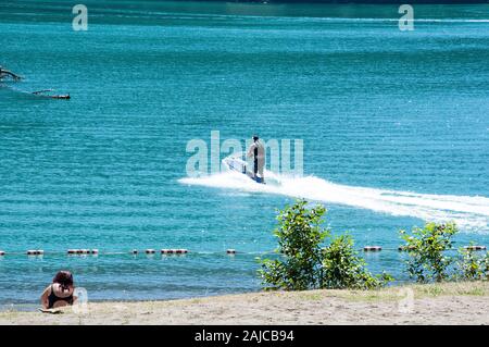 Fun Jet ski d'été sur le lac dans les eaux bleu profond un mec est profiter des sports nautiques les loisirs de plein air. Style de plaisir de vacances. Banque D'Images