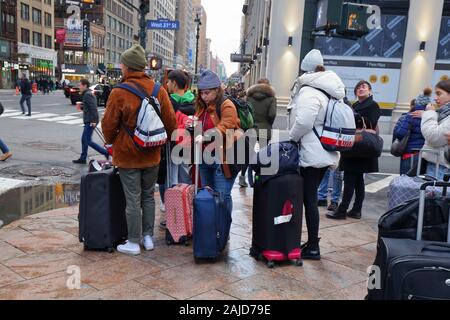 Les touristes avec des valises et bagages sur une rue à Manhattan, New York, NY Banque D'Images