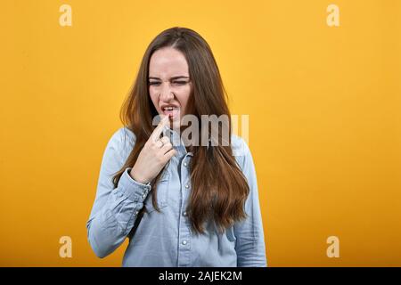 Déçu caucasian woman en gardant le doigt sur la langue, pinçant face Banque D'Images