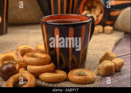 Bagels, petits chocolats, une tasse de thé et un tissu de fabrication locale sur un fond de bois close-up Banque D'Images