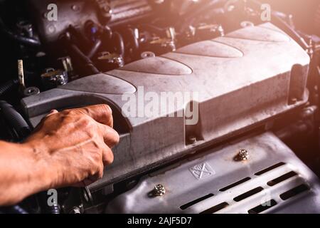 Main de technicien mécanicien auto entretien moteur et ouvrir le couvercle d'huile moteur sur la voiture dans le garage Banque D'Images