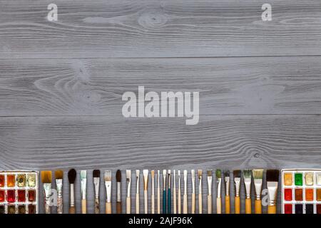 Set pinceaux à aquarelle et peintures sur table en bois gris Banque D'Images