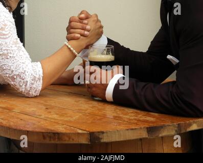 Bride and Groom tenir la main ensemble sur un tonneau en bois avec une tasse de café. Ensemble puissant. Banque D'Images