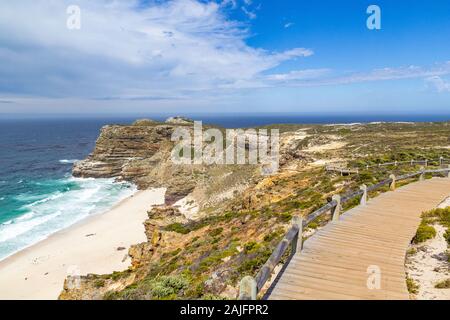 Passerelle en bois qui traverse la végétation fynbos avec vue sur l'océan et Dias Beach sur une journée ensoleillée, Cap de Bonne-Espérance, Afrique du Sud Banque D'Images