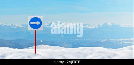Signpost, flèche vers la droite, direction obligatoire pour les skieurs épinglé à la neige. Des sommets enneigés en arrière-plan Banque D'Images