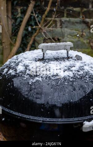 Électrique barbecue tambour recouvert de neige alors qu'il neige dans un jardin Banque D'Images