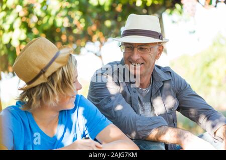 Man partager son expérience avec les gars dans le vignoble. Les gens les relations et la communication concept. L'homme en chapeau de paille vigneron parlant avec garçon. T Banque D'Images