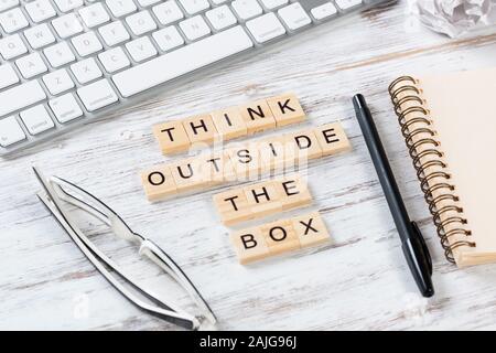 Penser en dehors de la boîte le cite avec des lettres sur des cubes. La vie toujours d'office l'espace de travail. Télévision jeter bureau en bois avec clavier de l'ordinateur, lunettes et pas en spirale Banque D'Images