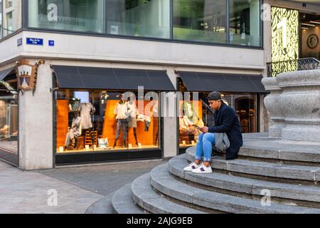 Genève, Suisse - le 14 avril 2019 : un adolescent est assis sur l'escalier dans la vieille ville et se penche sur son smartphone - image Banque D'Images