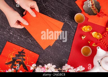 Concept de design janvier Nouvel An lunaire chinois - Woman holding, donner des enveloppes rouges (ang pow, hong bao) pour la chance de l'argent, top vue, télévision lay, overhe Banque D'Images