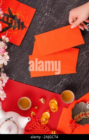 Concept de design janvier Nouvel An lunaire chinois - Woman holding, donner des enveloppes rouges (ang pow, hong bao) pour la chance de l'argent, top vue, télévision lay, overhe Banque D'Images