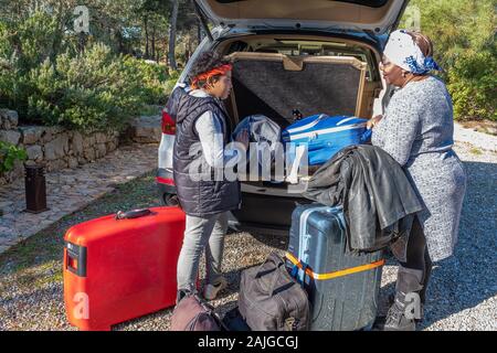 Femme loading valises dans la voiture, avec son fils, beaucoup de bagages Banque D'Images